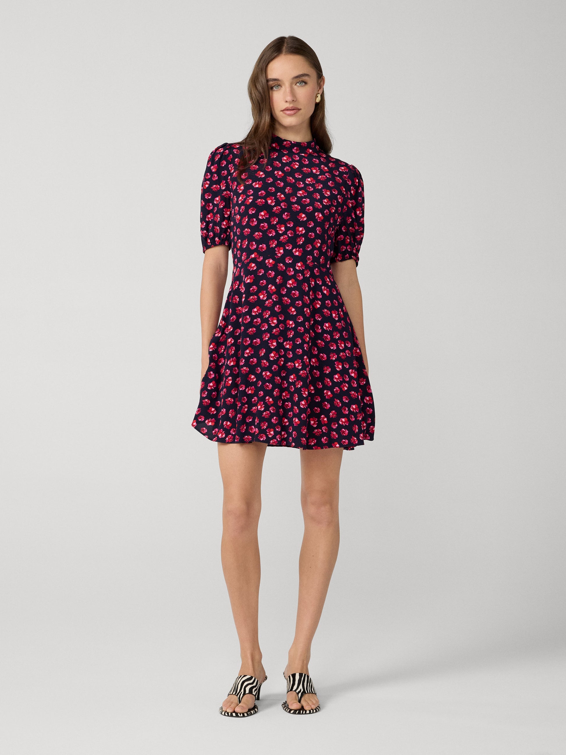 Woman wearing a black dress with pink floral pattern on a white background